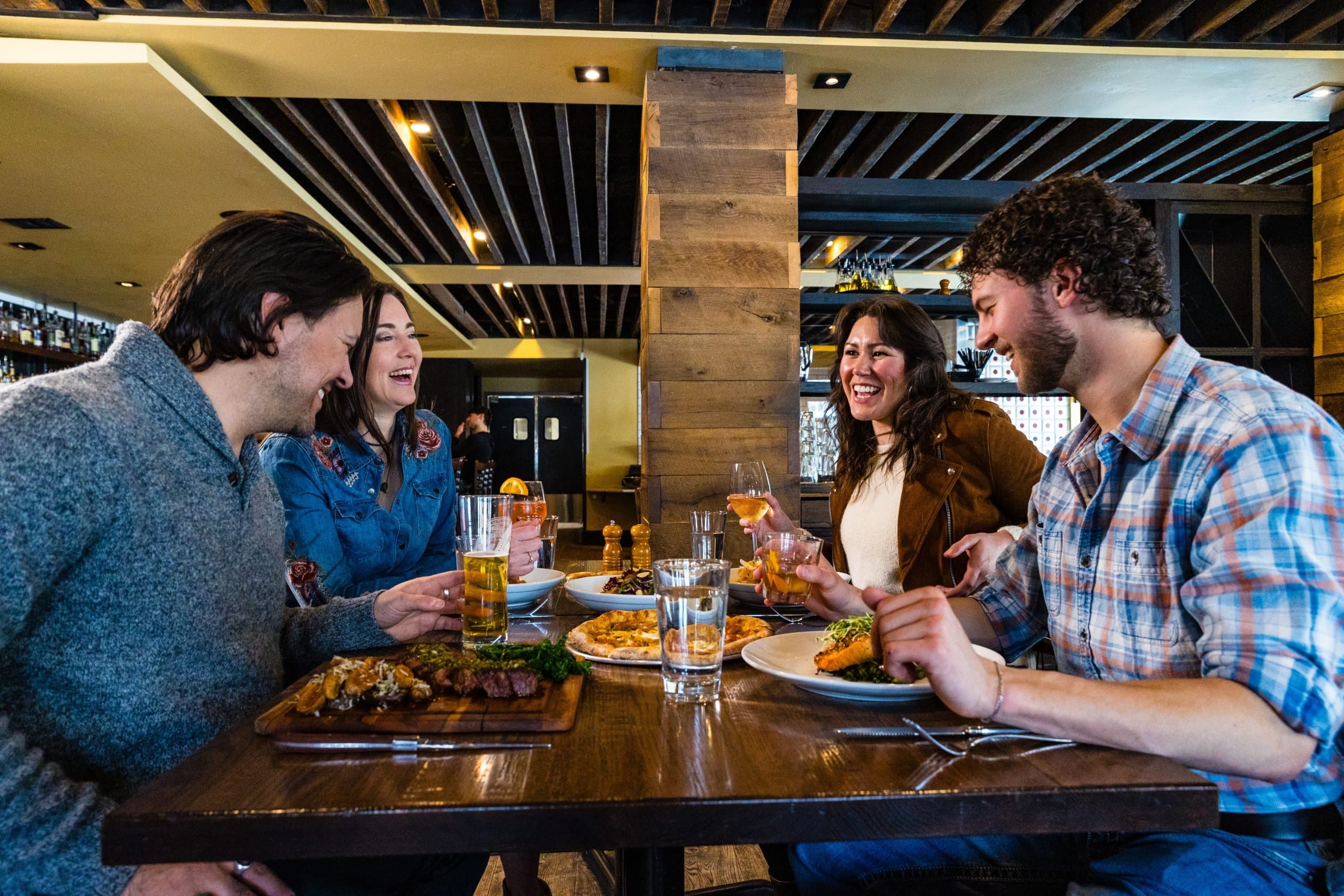 A group of people eating, laughing and having drinks at Il Villagio Osteria