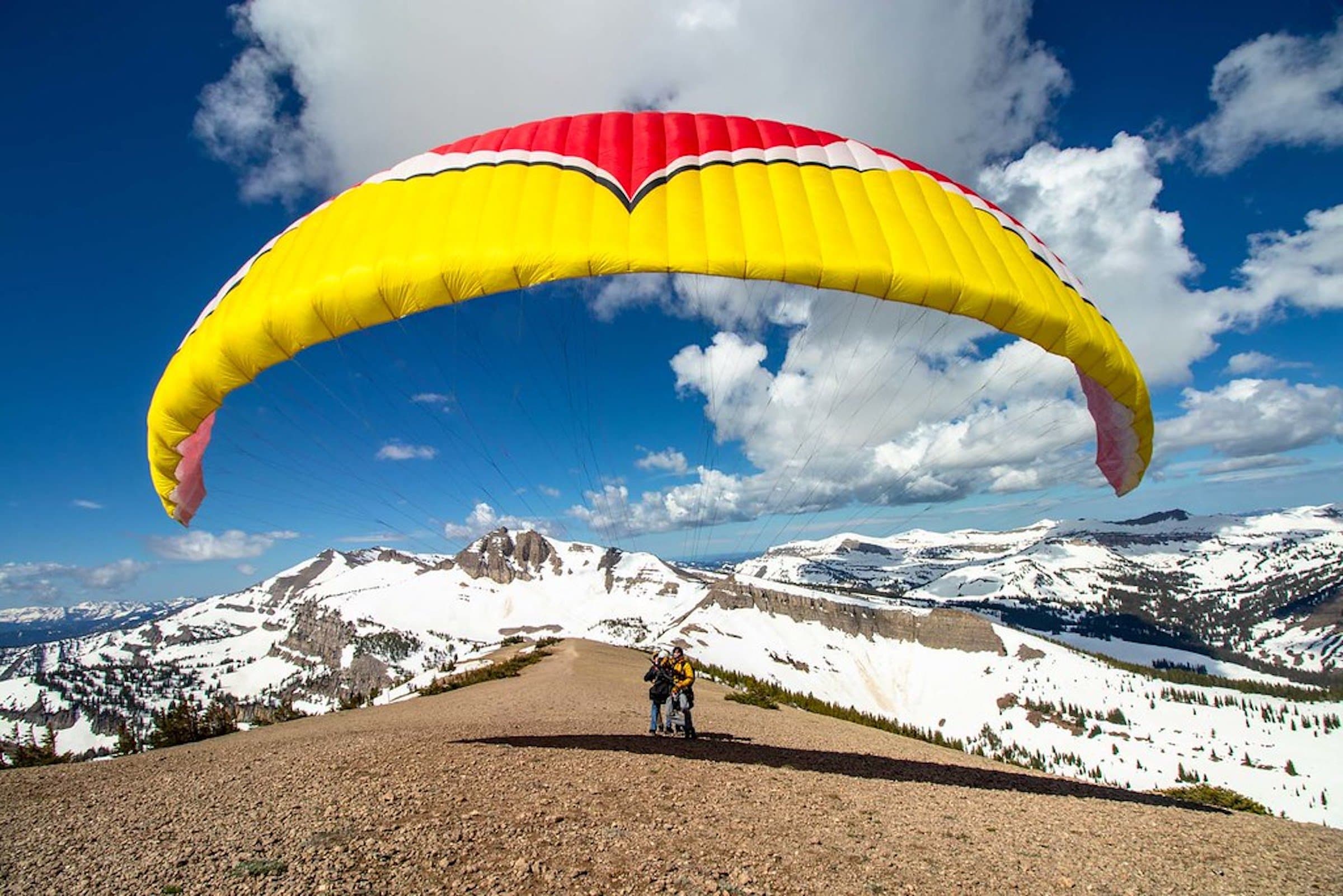 A couple landing from a paragliding experience in Jackson Hole.