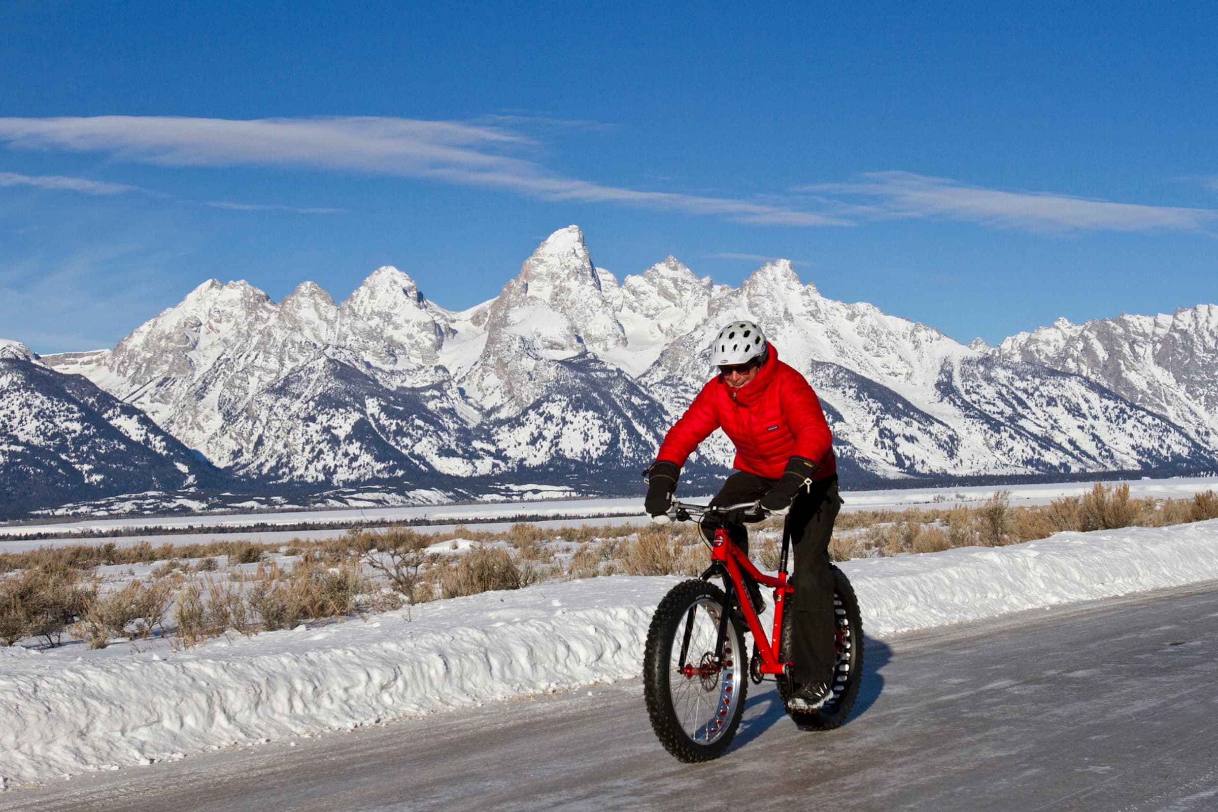 A man winter fat biking on an icy road in Jackson Hole, Wyoming.