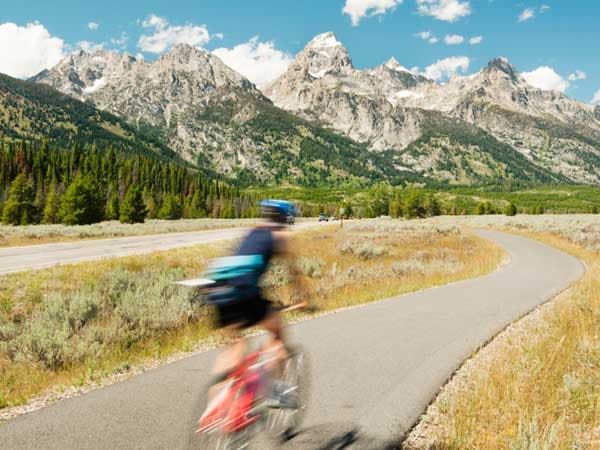 A fast moving cyclist biking past the Teton Mountains outside Jackson Hole Wyoming.