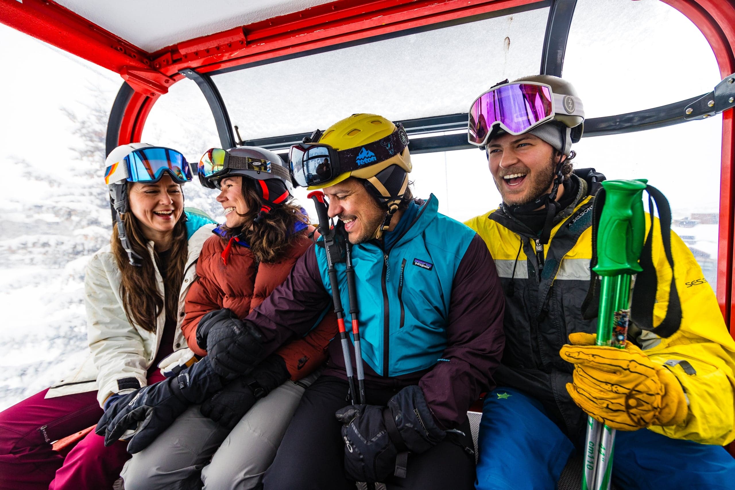 Two women and two men laugh and socialize on the ski lift going up the mountain with their gear at Jackson Hole Mountain Resort, Wyoming.