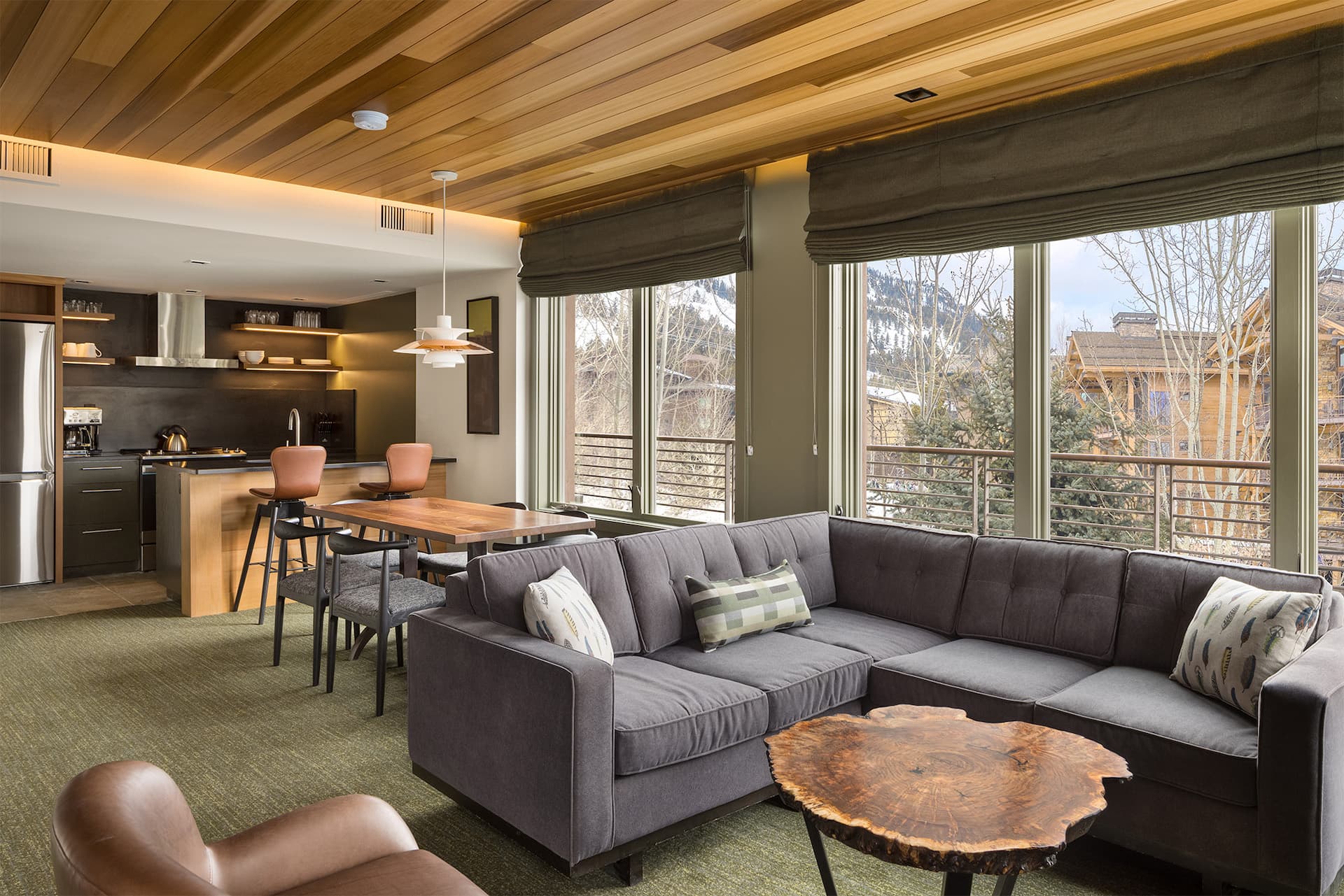 Living space inside a room at Terra Hotel with a table for 6, a fireplace with a sofa and chair, and a kitchen
