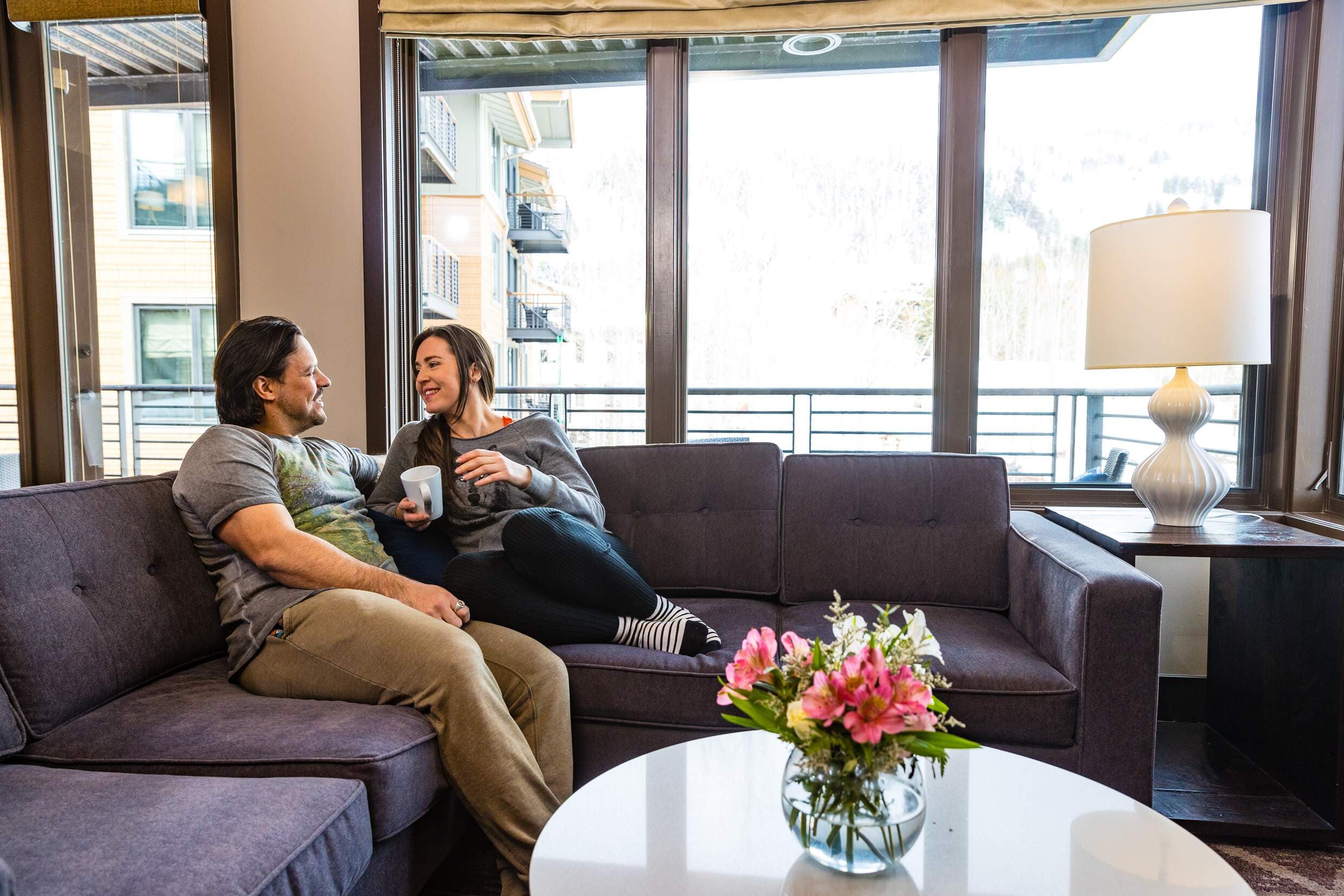 A couple lounging on the sofa couch their suite living room at Hotel Terra in Jackson Hole, Wyoming.