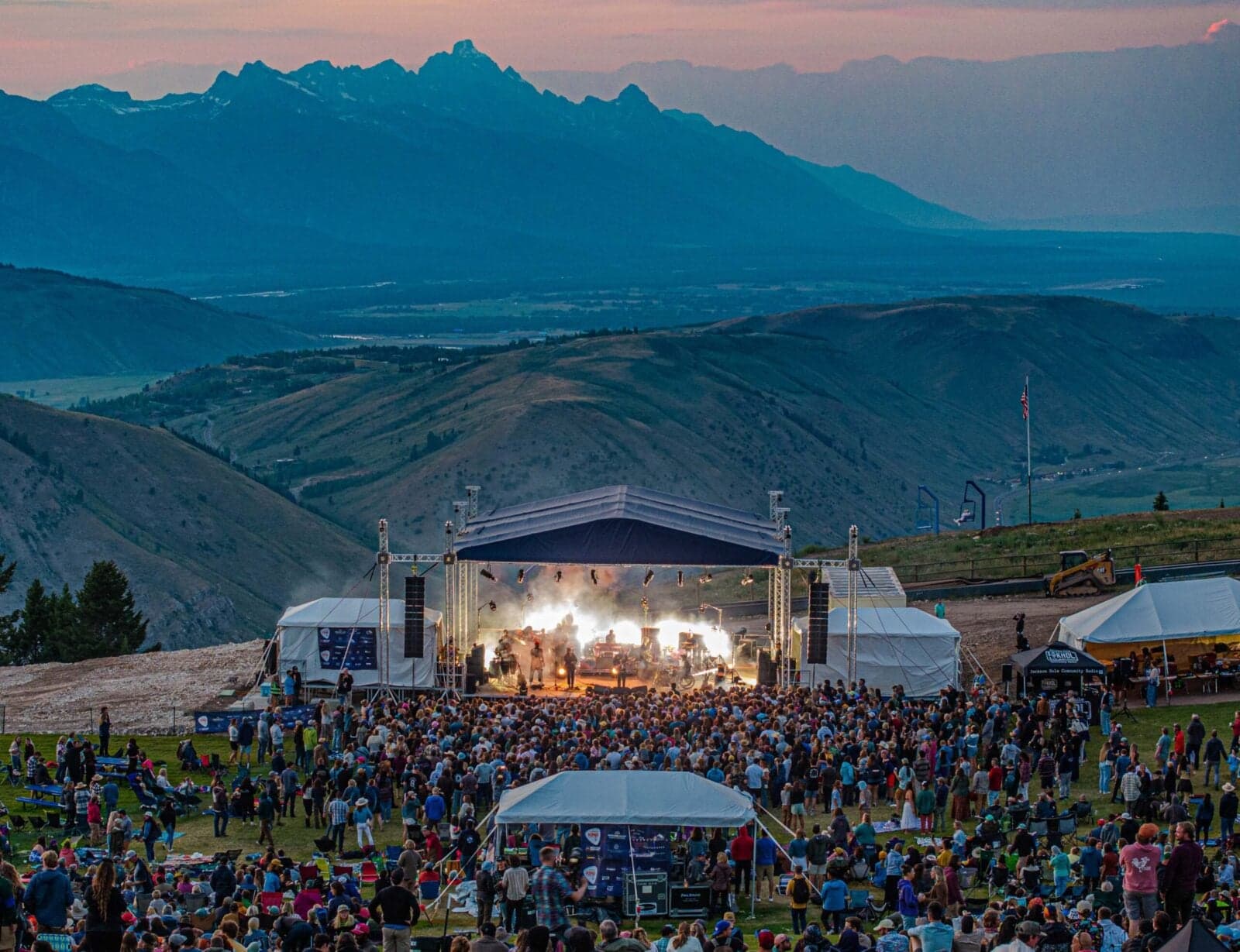 A Snow King Concert in a field at dusk with the Teton Mountains in the background.
