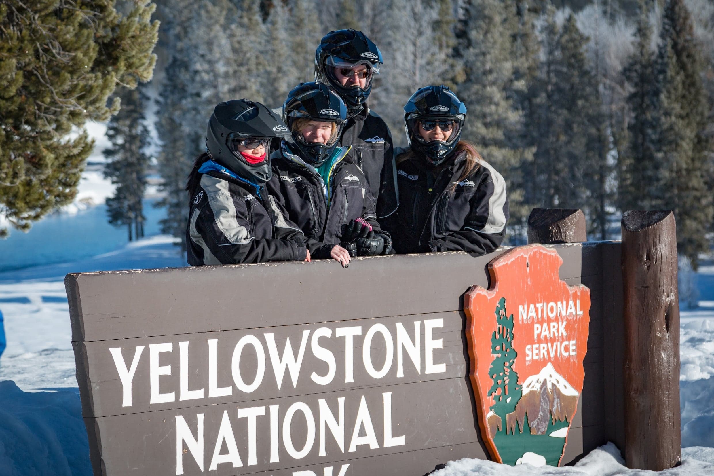 A snowmobile group post by the Yellowstone National Park sign in Wyoming