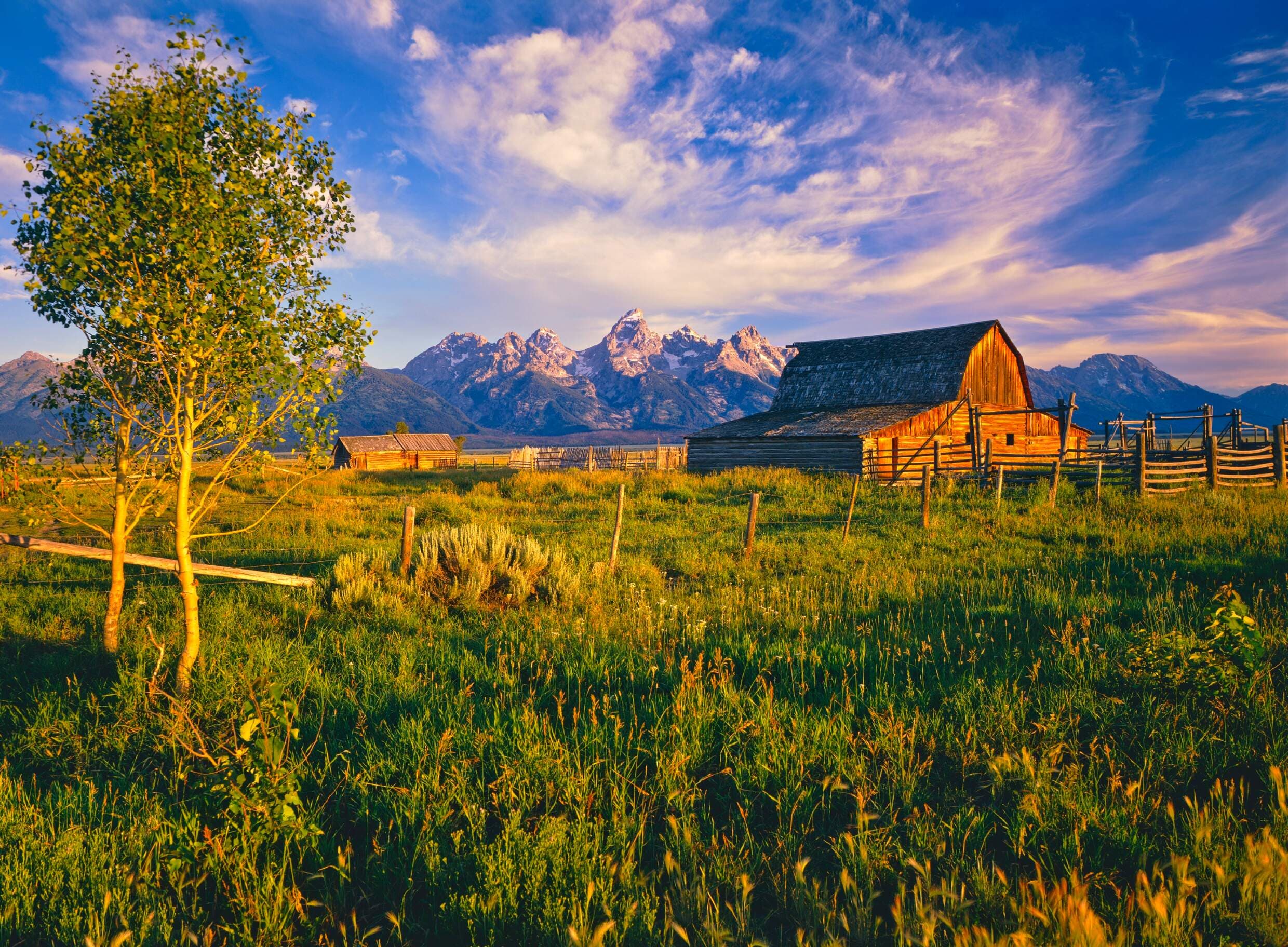The Tetons mountain peaks behind Moulton Barn at sunset in Grand Teton National Park in Wyoming.