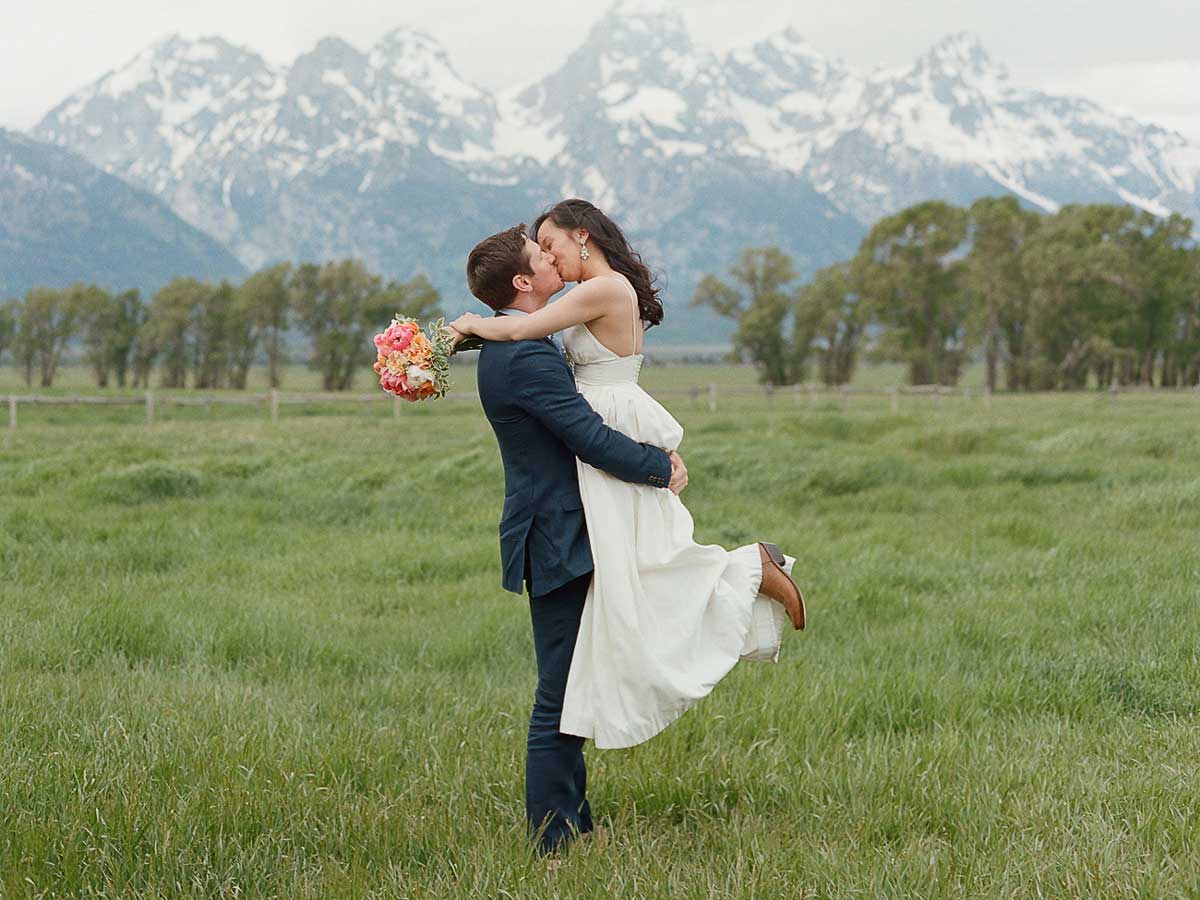 Bride And Groom Kiss With The Tetons In The Background.